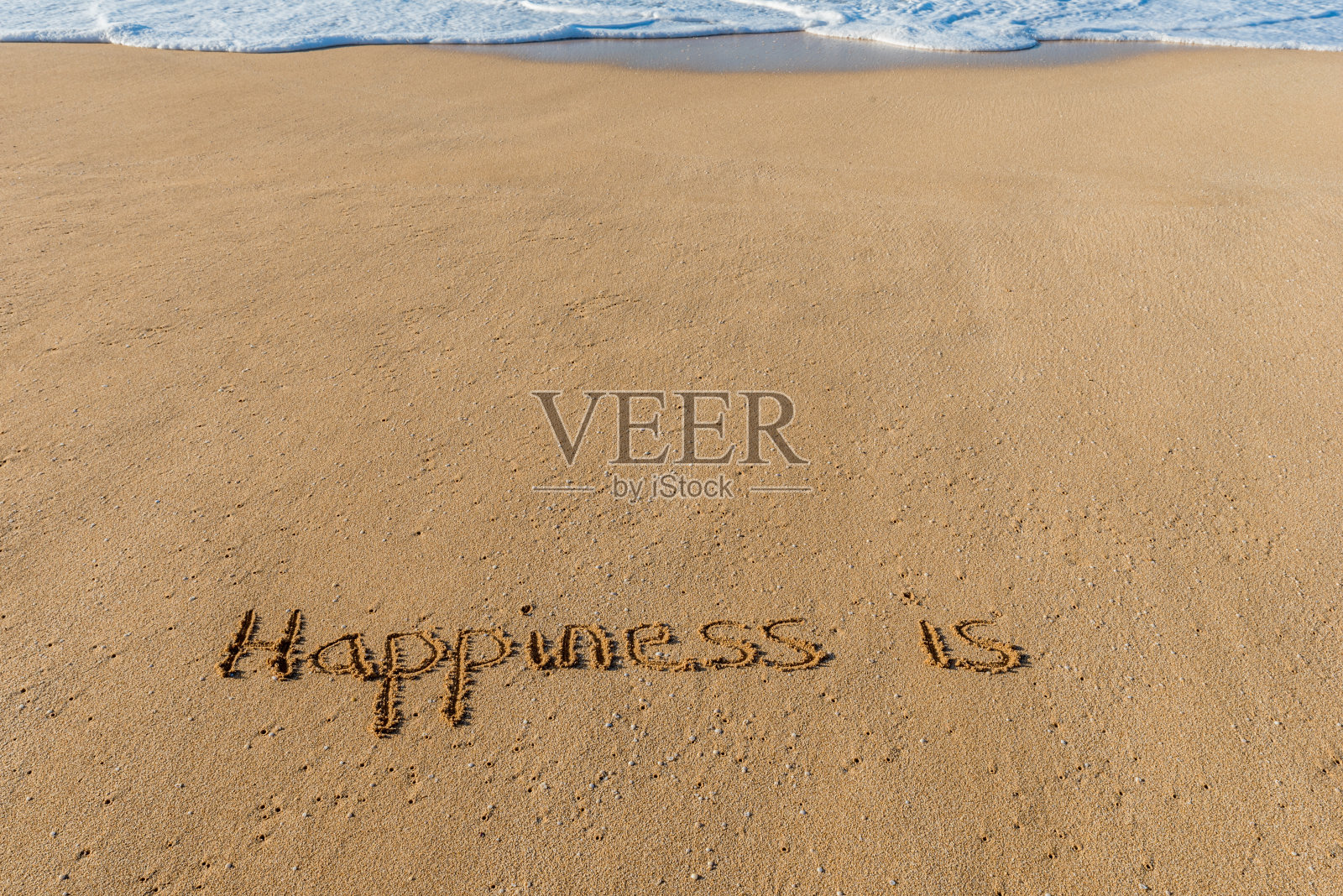 “幸福就是”写在沙滩上用波浪冲刷着照片摄影图片