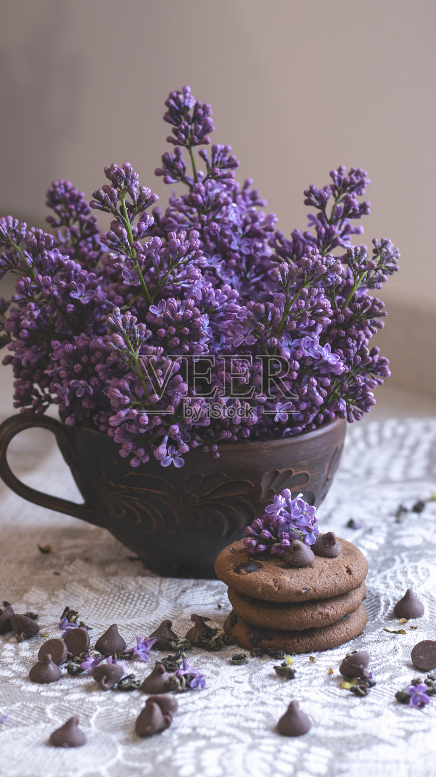 装饰组成与一束紫丁香在一个明亮的厨房内部。泥杯茶和巧克力蛋糕。花瓶里的一束紫丁香。春天的花背景与紫丁香。美学照片摄影图片