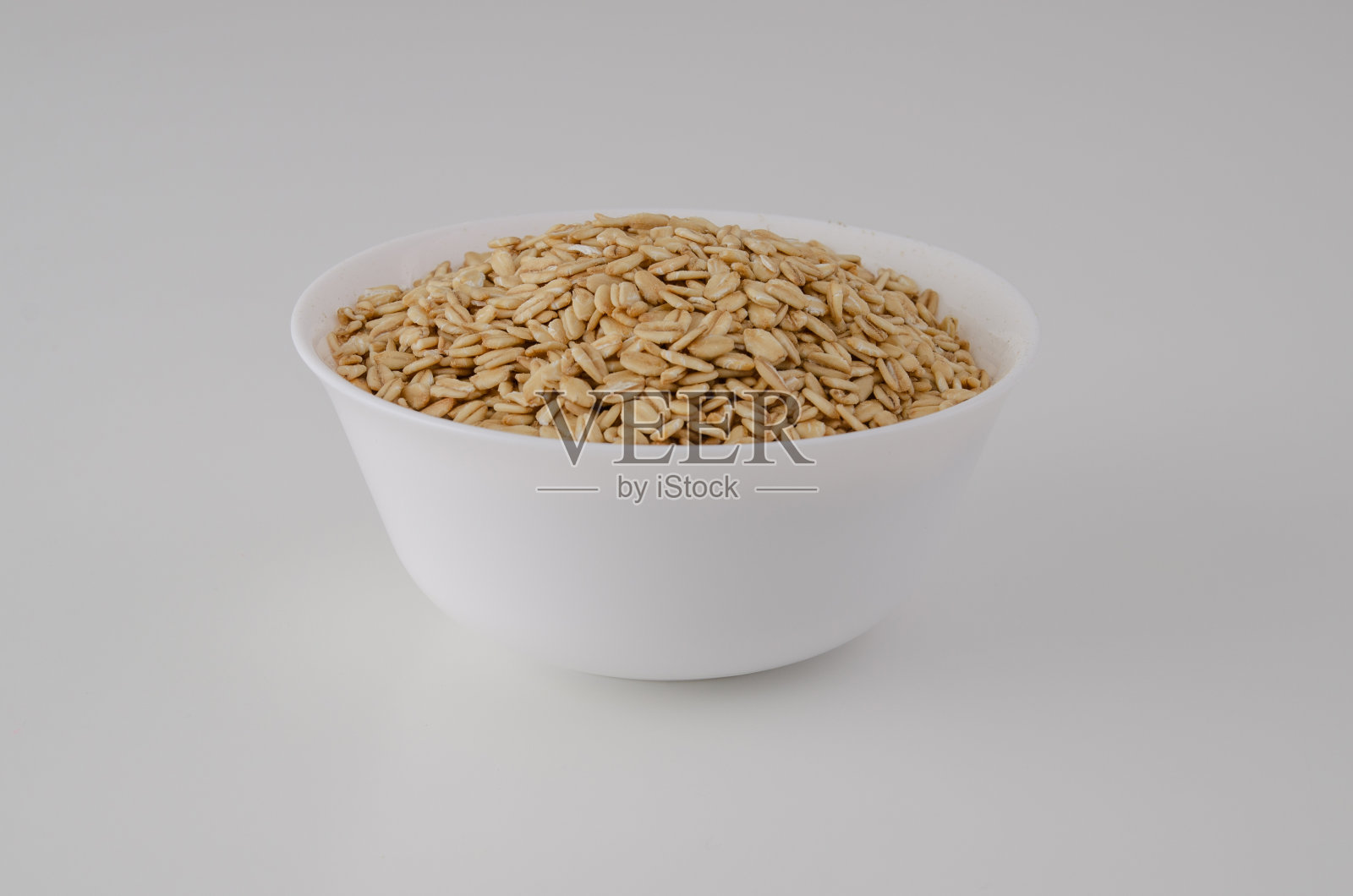 白色盘子和干燕麦片在一个干净的背景。健康的生活方式。照片摄影图片