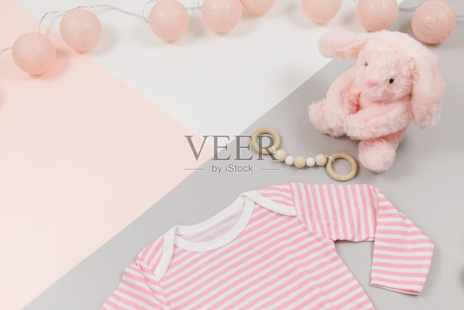 粉红色的泰迪熊，粉红色的棉质紧身衣和木制的新生儿玩具。模拟了照片摄影图片