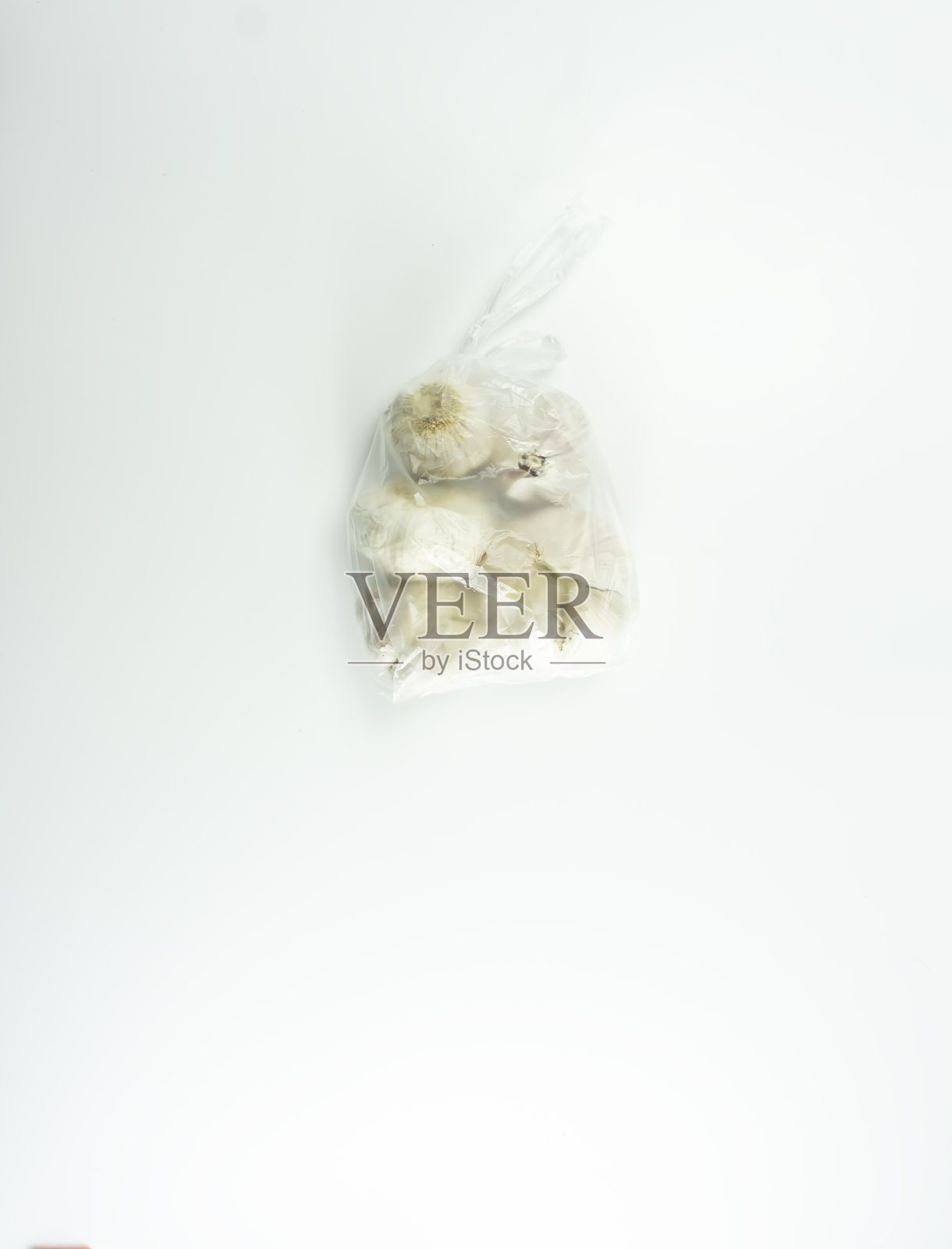 大蒜包在透明的白色塑料在白色的背景照片摄影图片