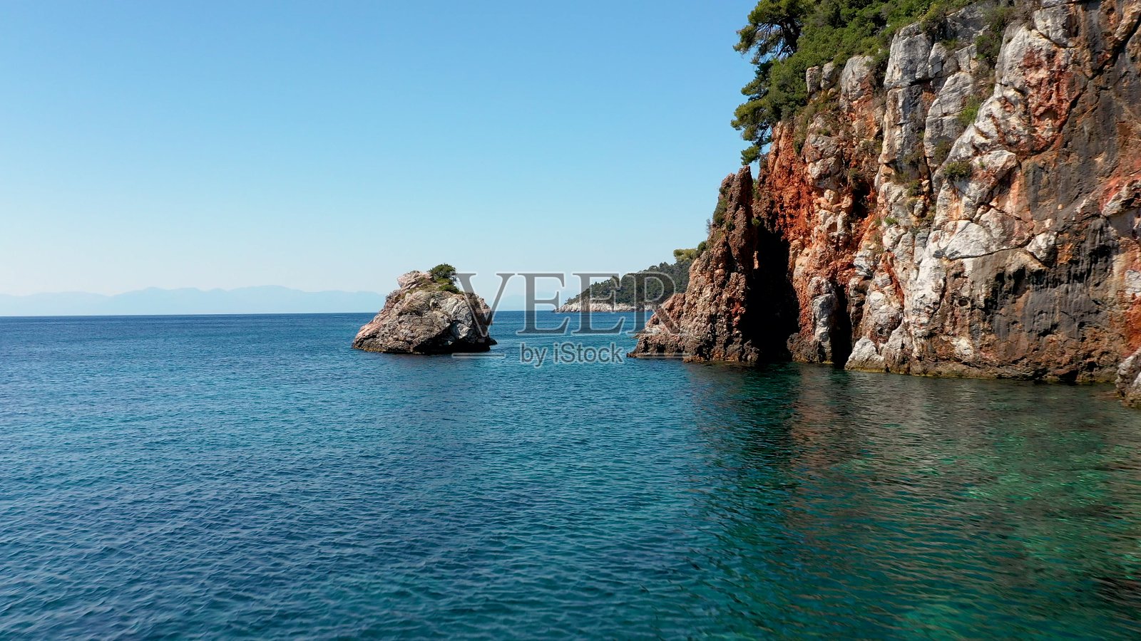 在希腊斯科佩洛斯岛，无人机俯瞰岩石嶙峋的海岸线、清澈的爱琴海水域、旅游海滩和大量的绿色植物。这是许多类似的希腊岛屿的典型景观。照片摄影图片