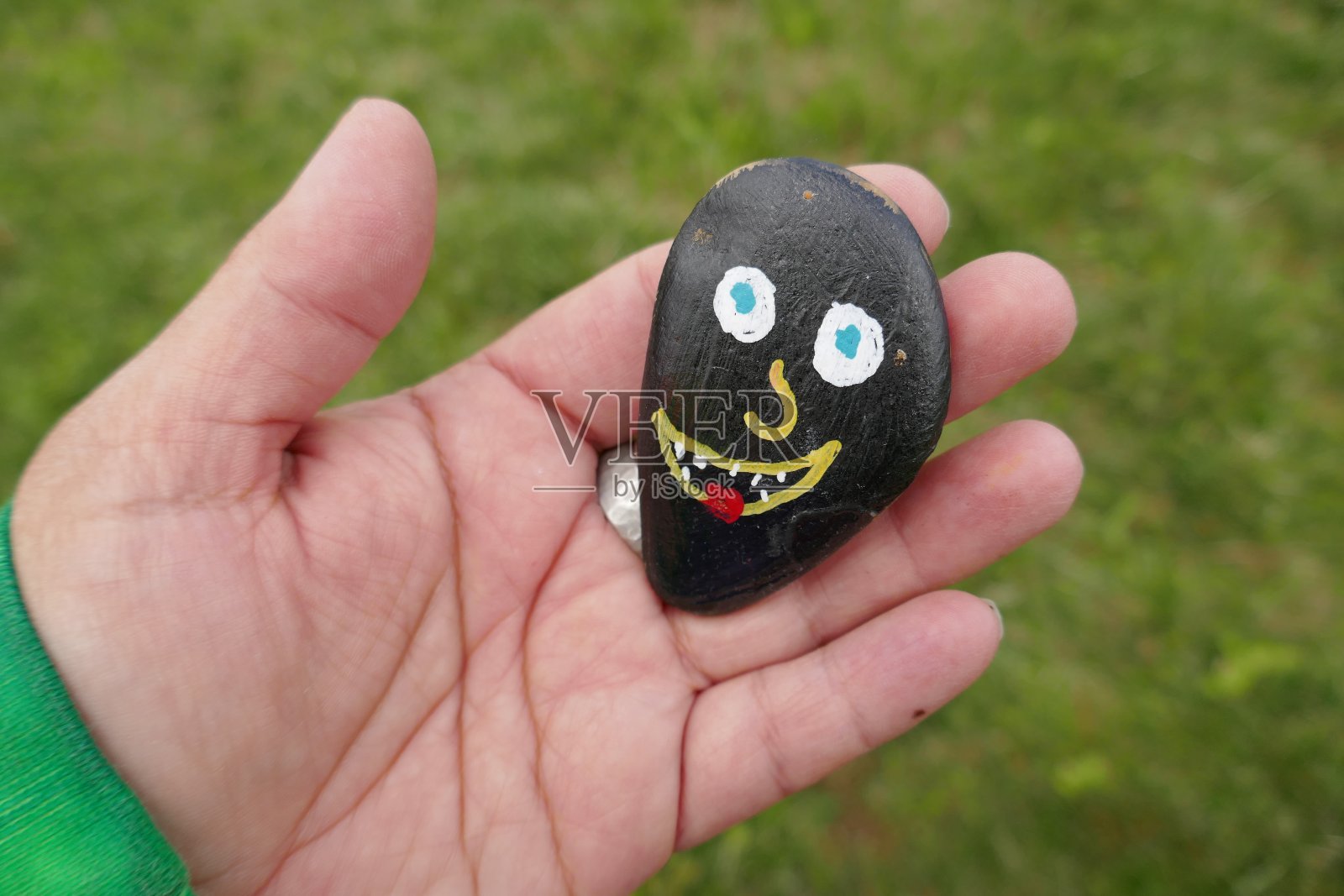 傻笑的脸画在善良的岩石上，握在女人的手里照片摄影图片