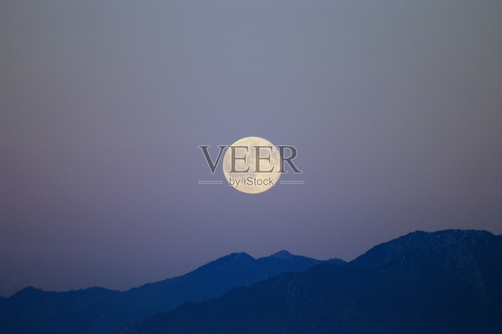 蓝色的岩石山脉上升起的满月照片摄影图片