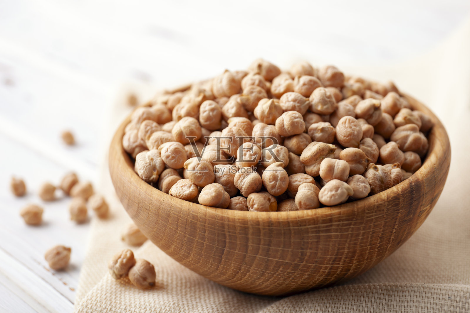 木桌上的碗里装着生鹰嘴豆。健康食品的概念照片摄影图片