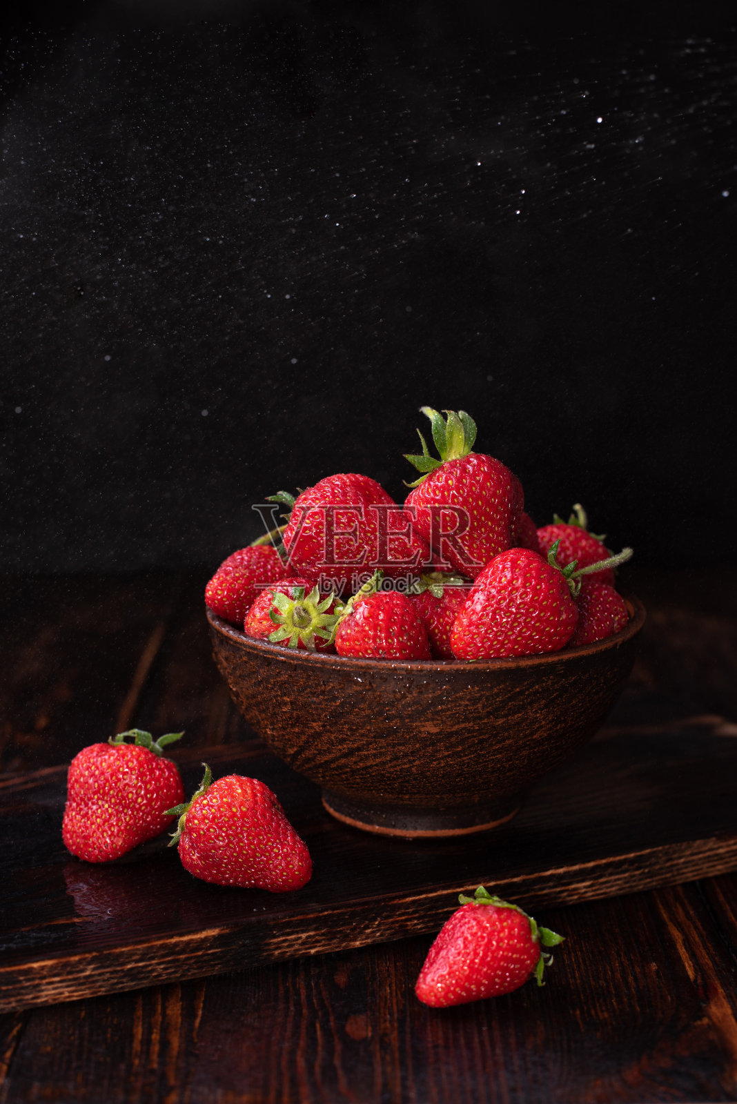 新鲜的草莓放在一个碗里，深色的木制背景，夏天的概念。照片摄影图片