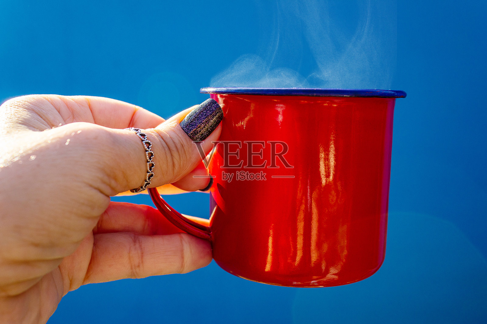 手里拿着一个杯子。照片摄影图片