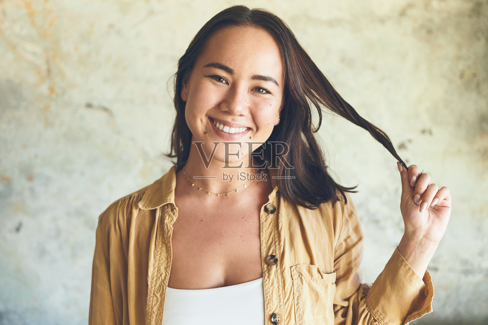 一个自信的年轻女子靠墙站着的肖像照片摄影图片