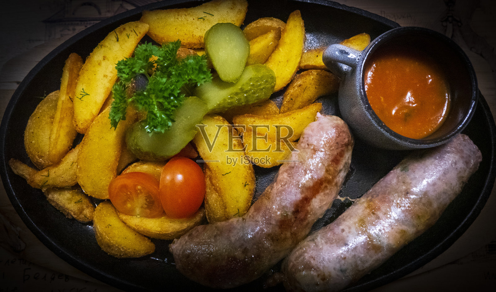 香肠和爱达荷土豆，切成片，在煎锅里煎。照片摄影图片