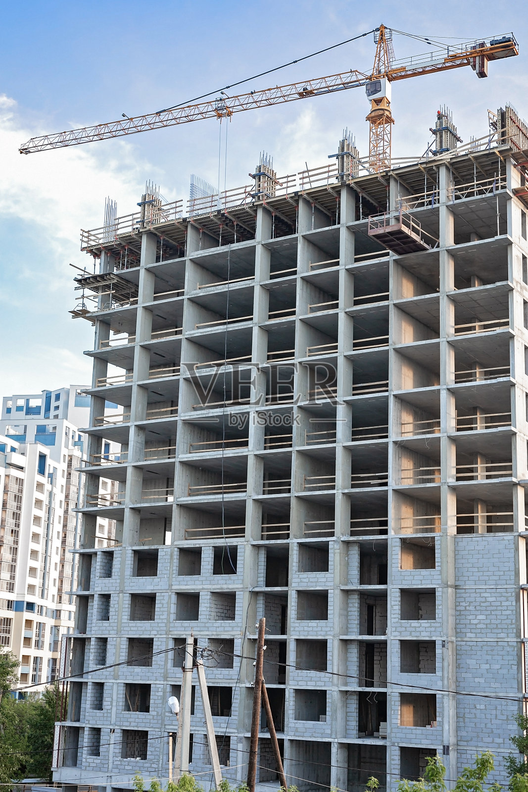 在大城市里建造多层公寓。蓝天背景下的施工起重机。建筑、城市和商业地产主题。垂直拍摄照片摄影图片