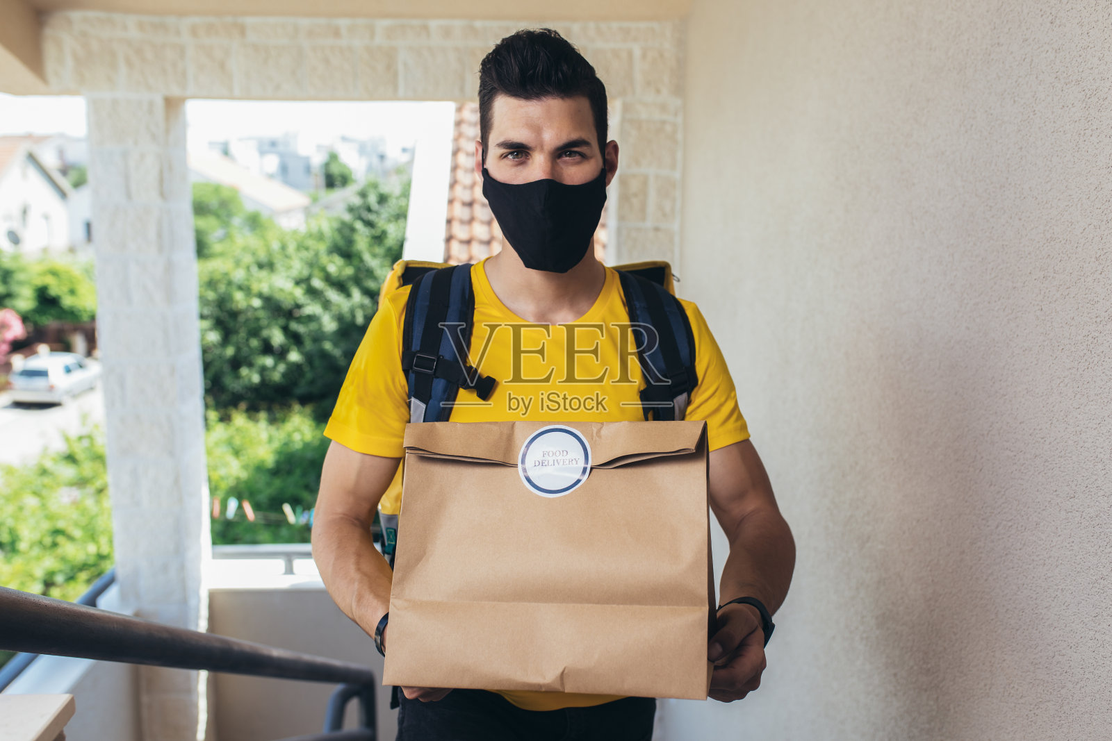 戴着防护面具的男子在网上送杂货订单。照片摄影图片