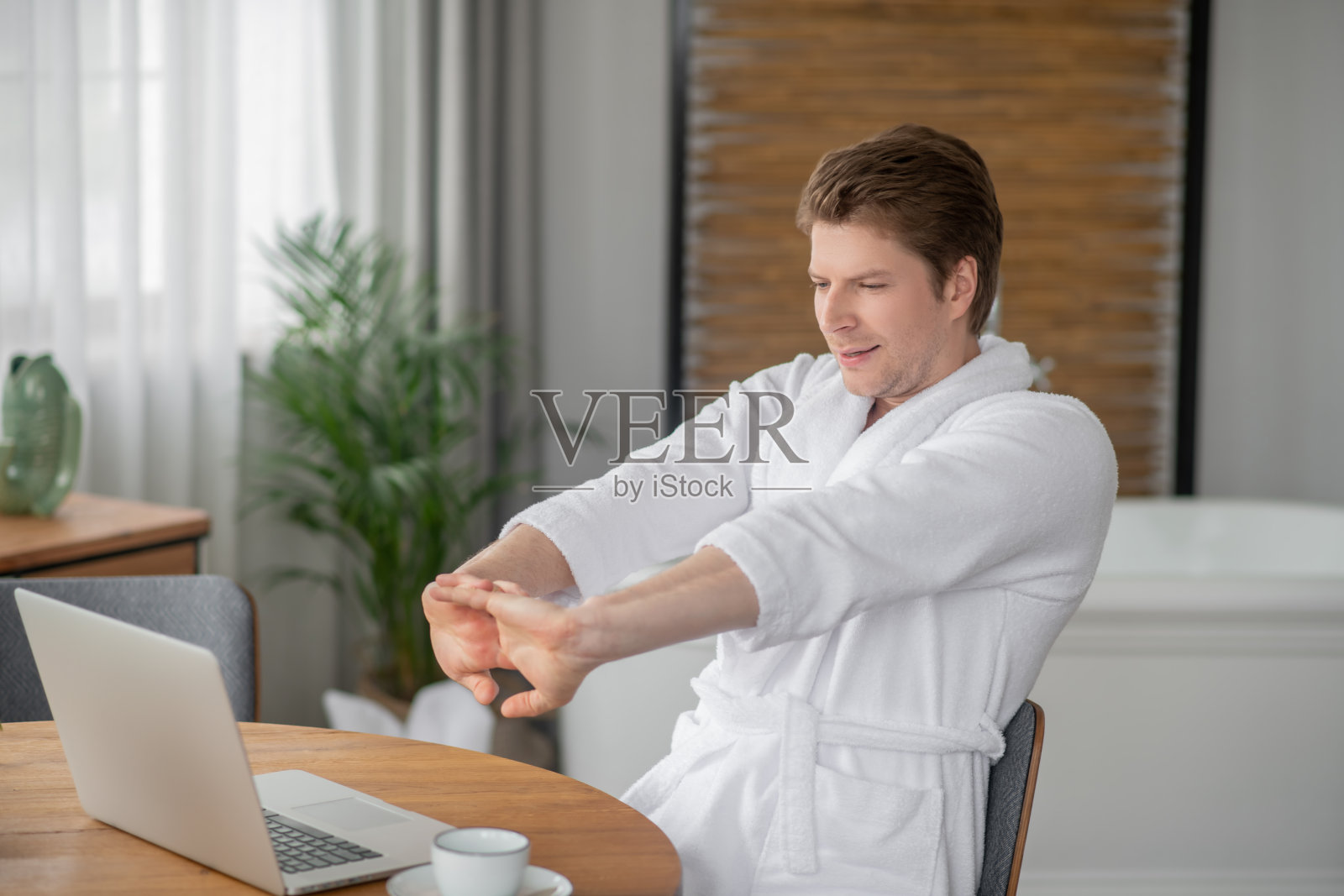 一个男人坐在笔记本电脑前伸伸胳膊照片摄影图片