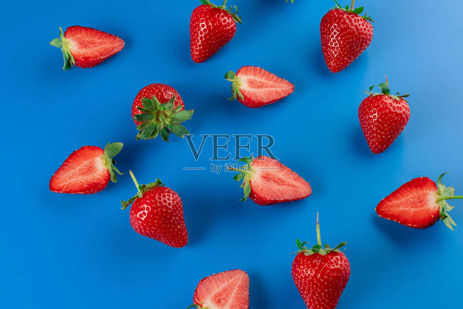 蓝色背景上的草莓片和整个草莓。季节性的浆果。照片摄影图片