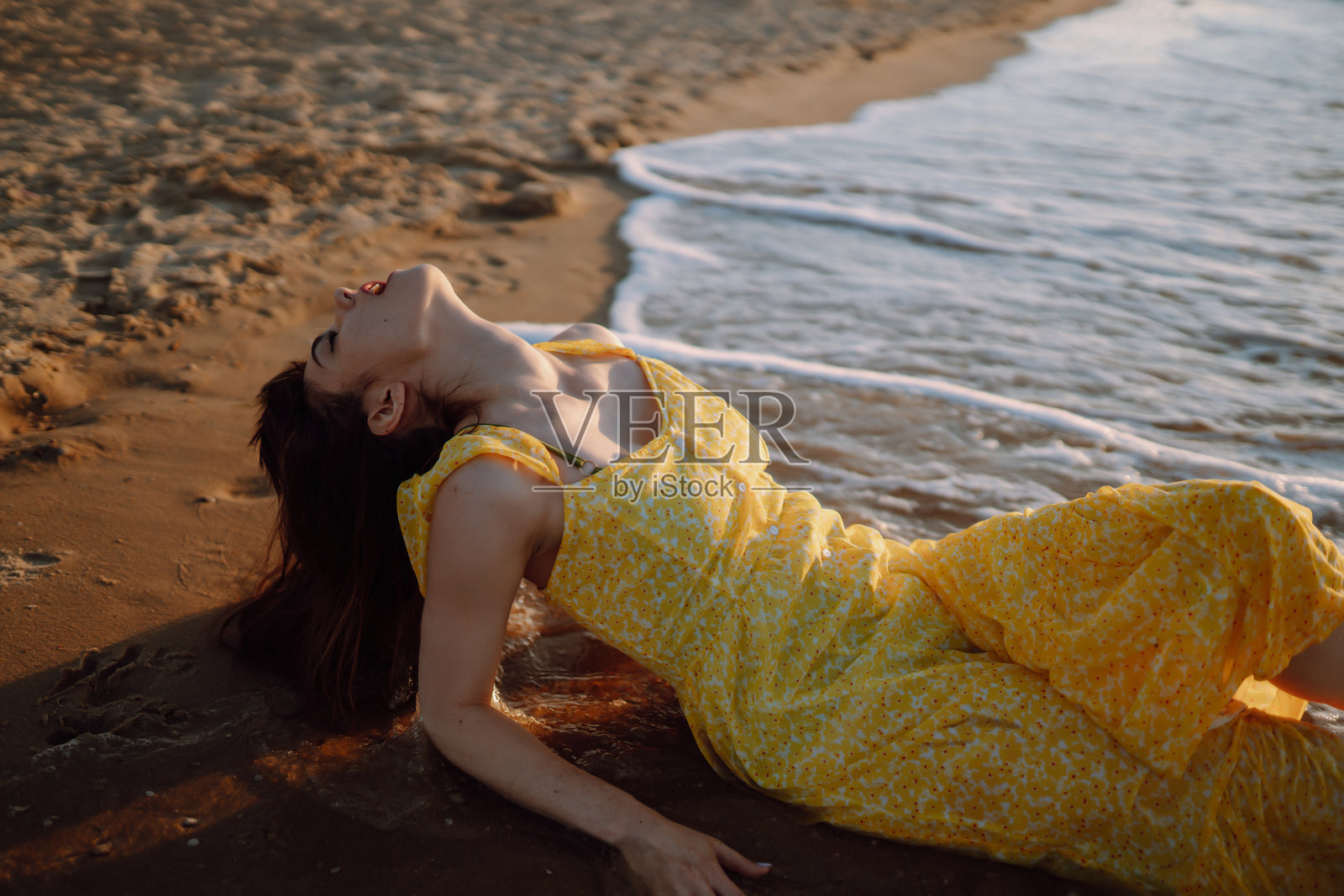 年轻女子在海滩上欣赏美丽的日落。女性，有吸引力和感官轮廓。照片摄影图片