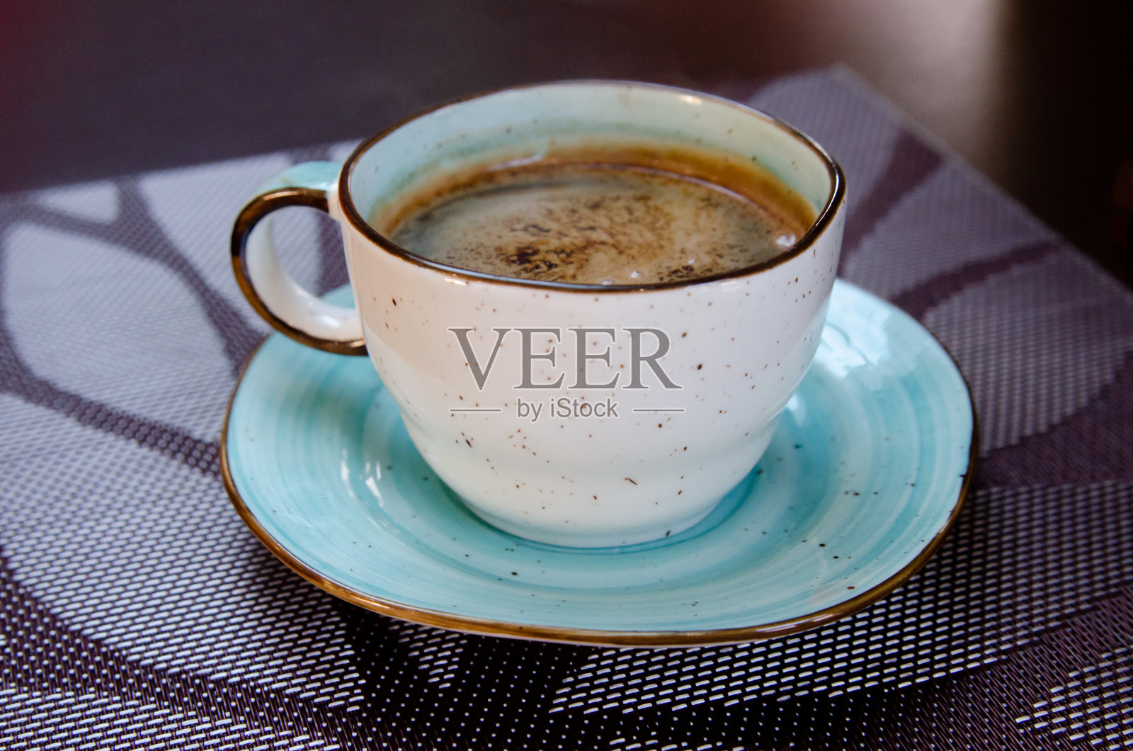 桌上有棕色桌布，杯子里有泡沫的咖啡照片摄影图片