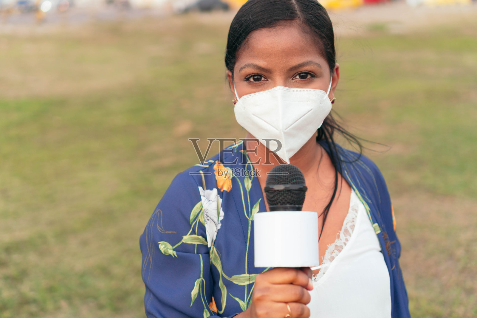 戴面具拿着麦克风的女记者照片摄影图片