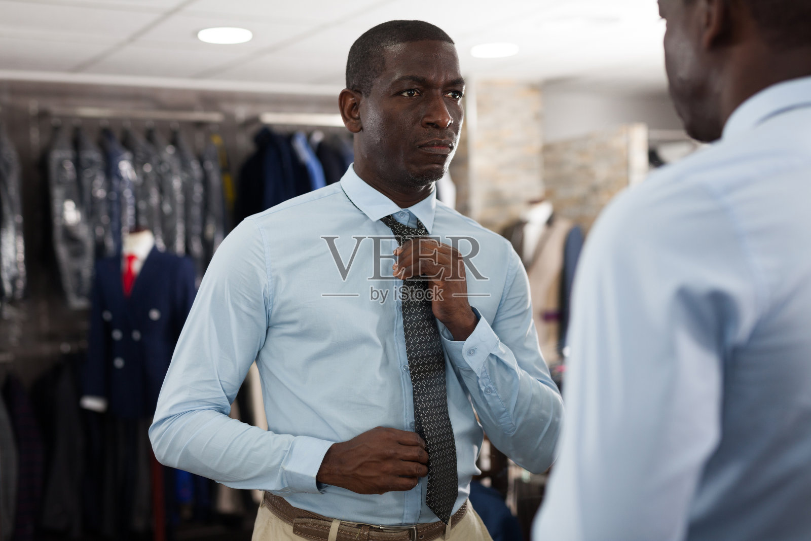 自信的男性顾客在男装店里选择时尚的米色套装照片摄影图片