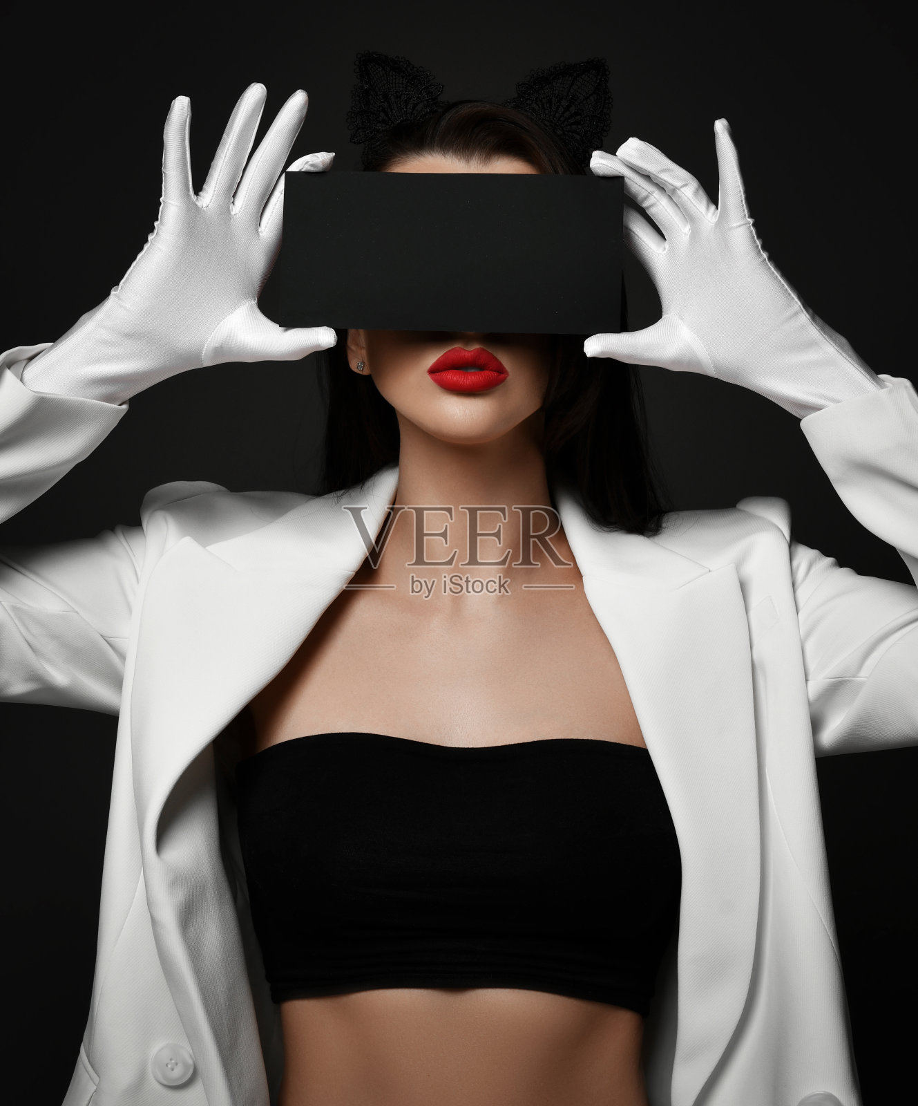 美丽的黑发女人美容师模特在白色的夹克和手套与红色的嘴唇持有黑色的面具在眼睛照片摄影图片