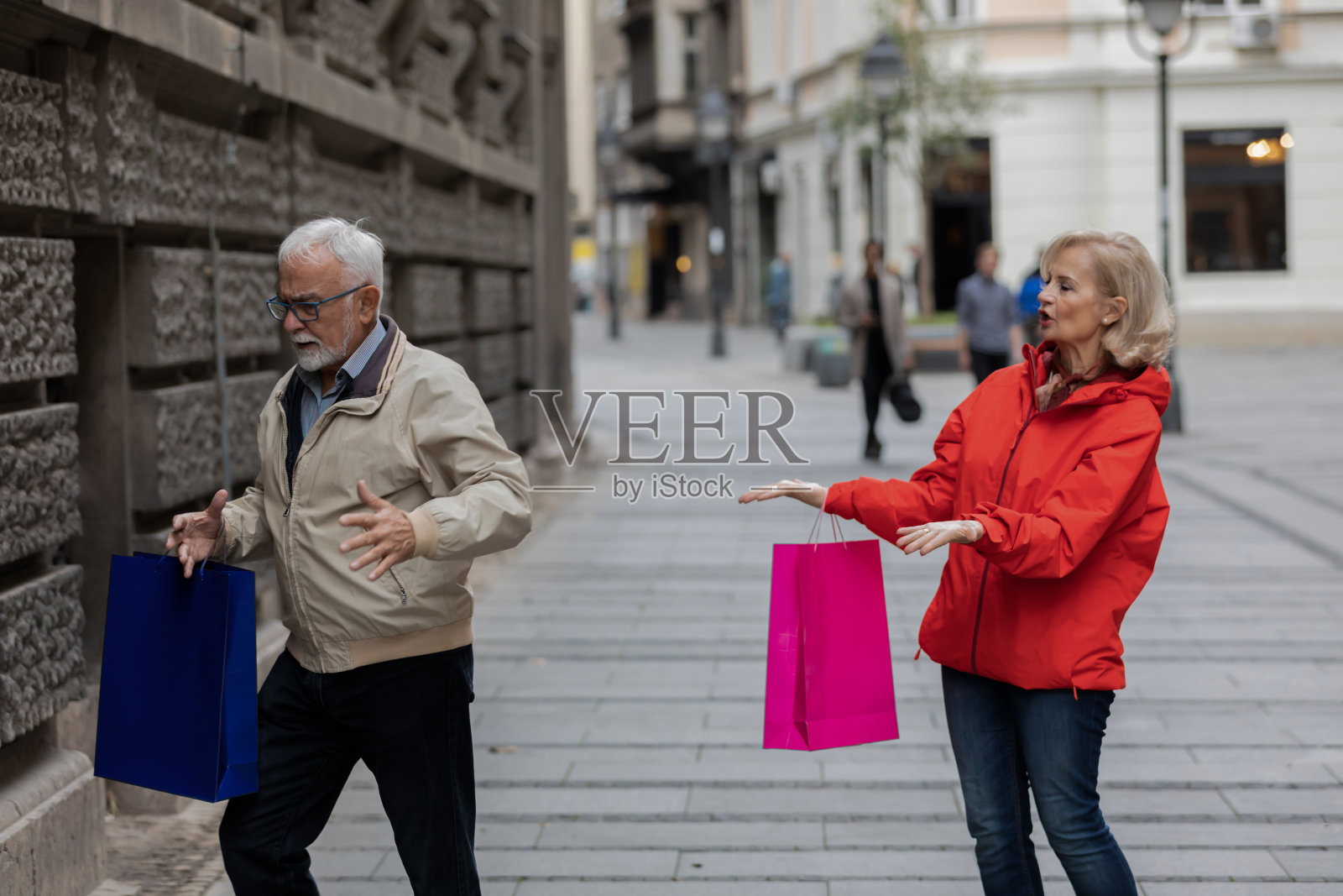 在城市区域散步时与愤怒的妻子争吵的年长的男人照片摄影图片