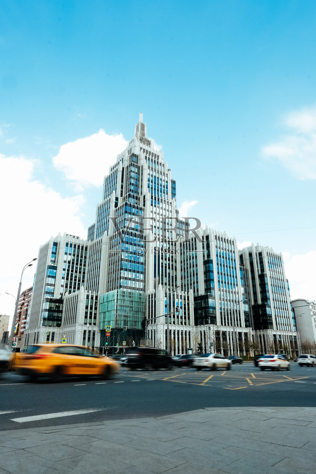 时髦的现代蓝色玻璃摩天大楼在t城市和黄色出租车行驶在城市街道上的速度模糊。大城市的生活活力。照片摄影图片