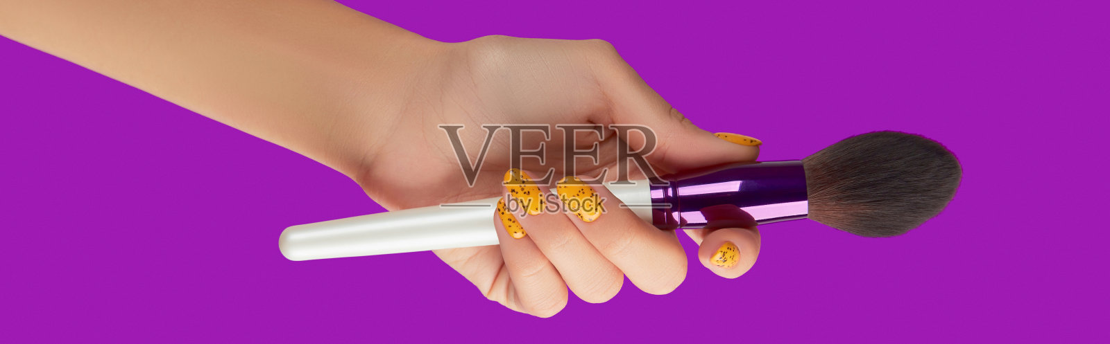 专业化妆刷在女性手上的紫色背景上照片摄影图片