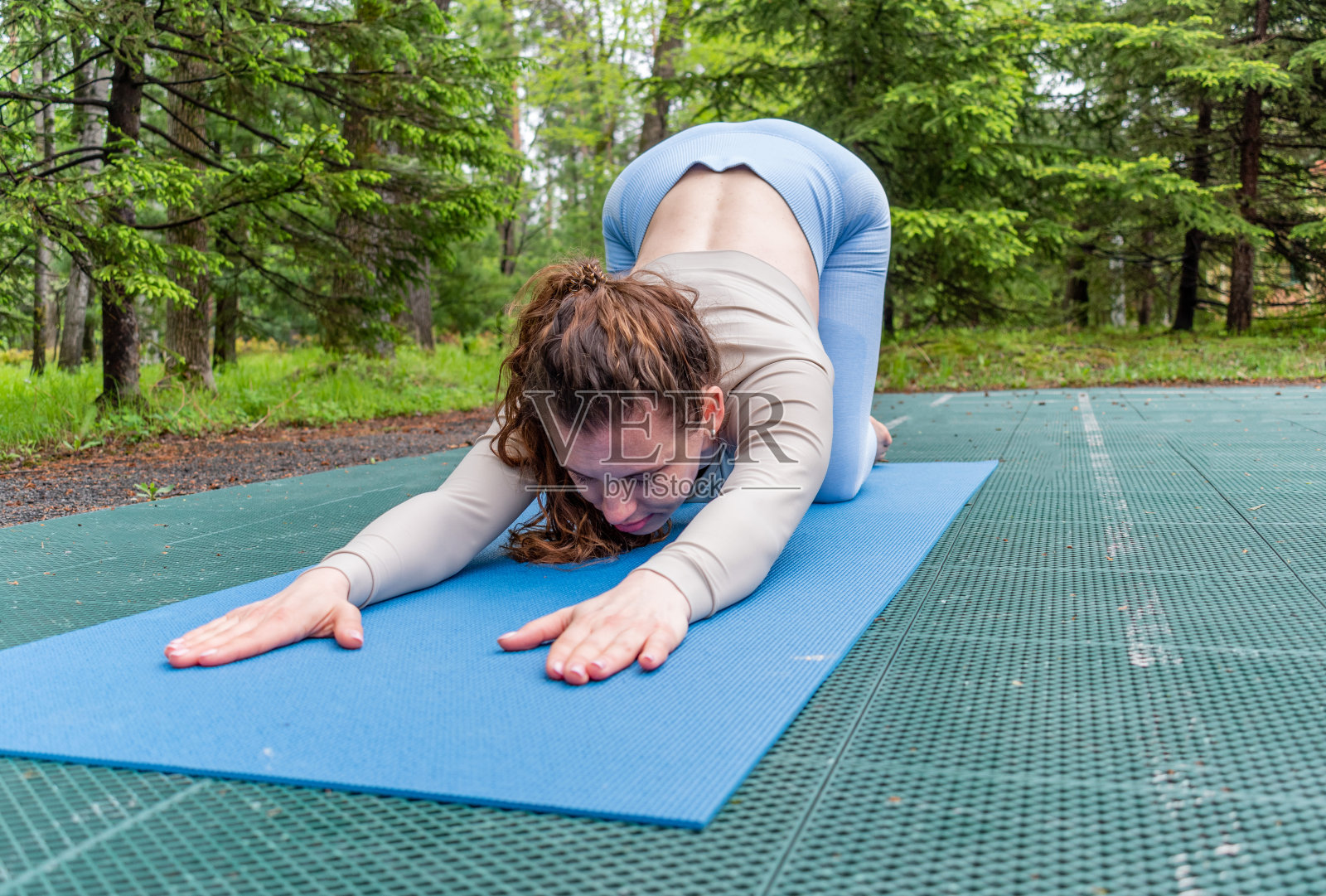 一个红头发的女人在公园里做瑜伽。运动服装和瑜伽垫。复制空间照片摄影图片
