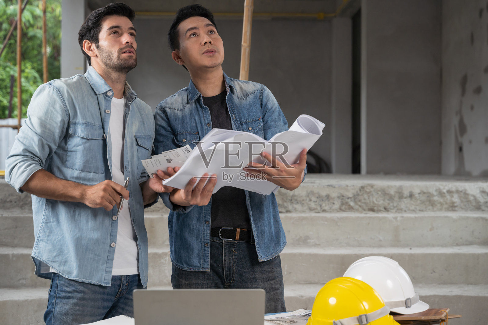 工程团队在建筑现场开会并在笔记本电脑上进行讨论。团队现场的架构检查员，并共同讨论照片摄影图片