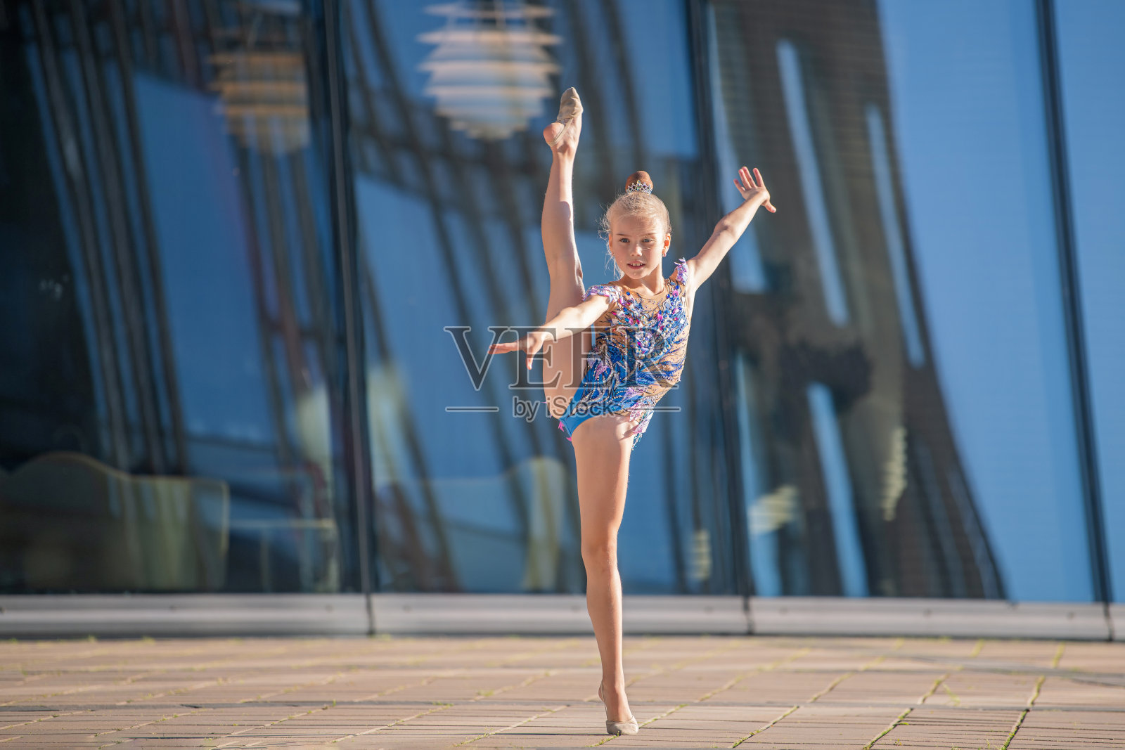 一个学校年龄的女孩体操运动员穿着漂亮的异装和黑色的套装表演没有一个设备。照片摄影图片