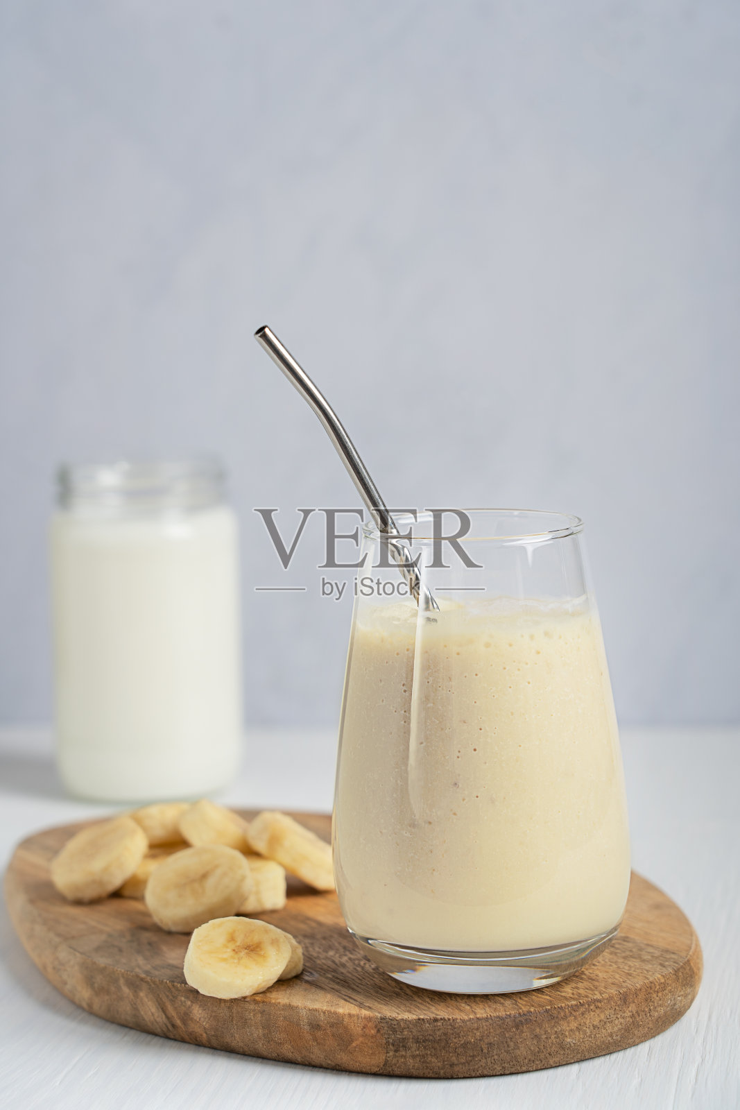 在白色木桌上的砧板上盛满了由酸奶和成熟香蕉水果混合而成的印度当地自制的甜饮料照片摄影图片