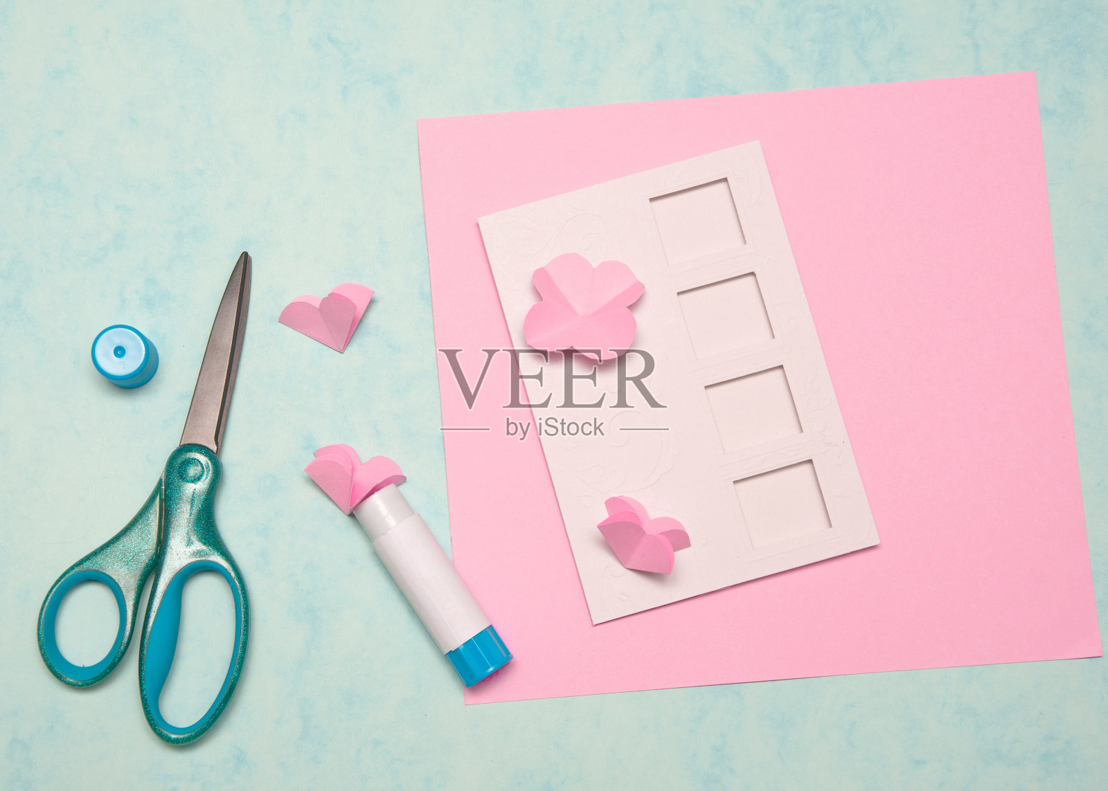 DIY明信片情人节，婚礼装饰，第六步，剪贴框背景。手工礼品贺卡创建，剪切和粘贴，在蓝色背景上的牛皮纸。平躺照片摄影图片