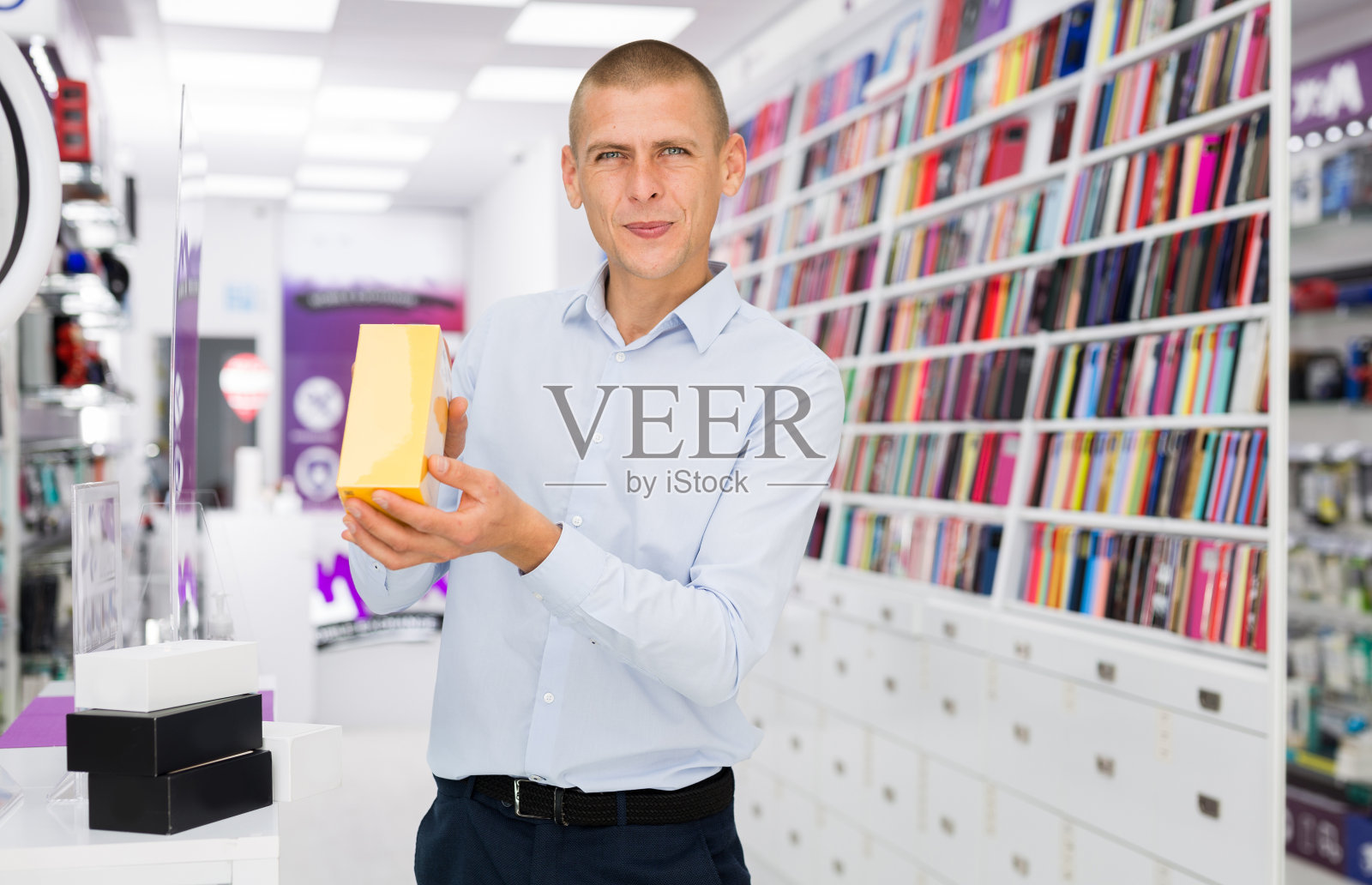 在电子商店，微笑的男性拿着一个手机盒子照片摄影图片