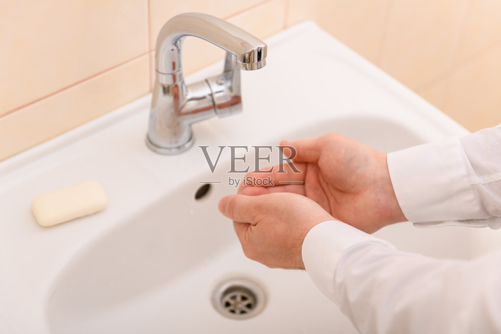 用肥皂或凝胶在流动的水下洗手，清洁卫生，男子的手穿白衬衫照片摄影图片