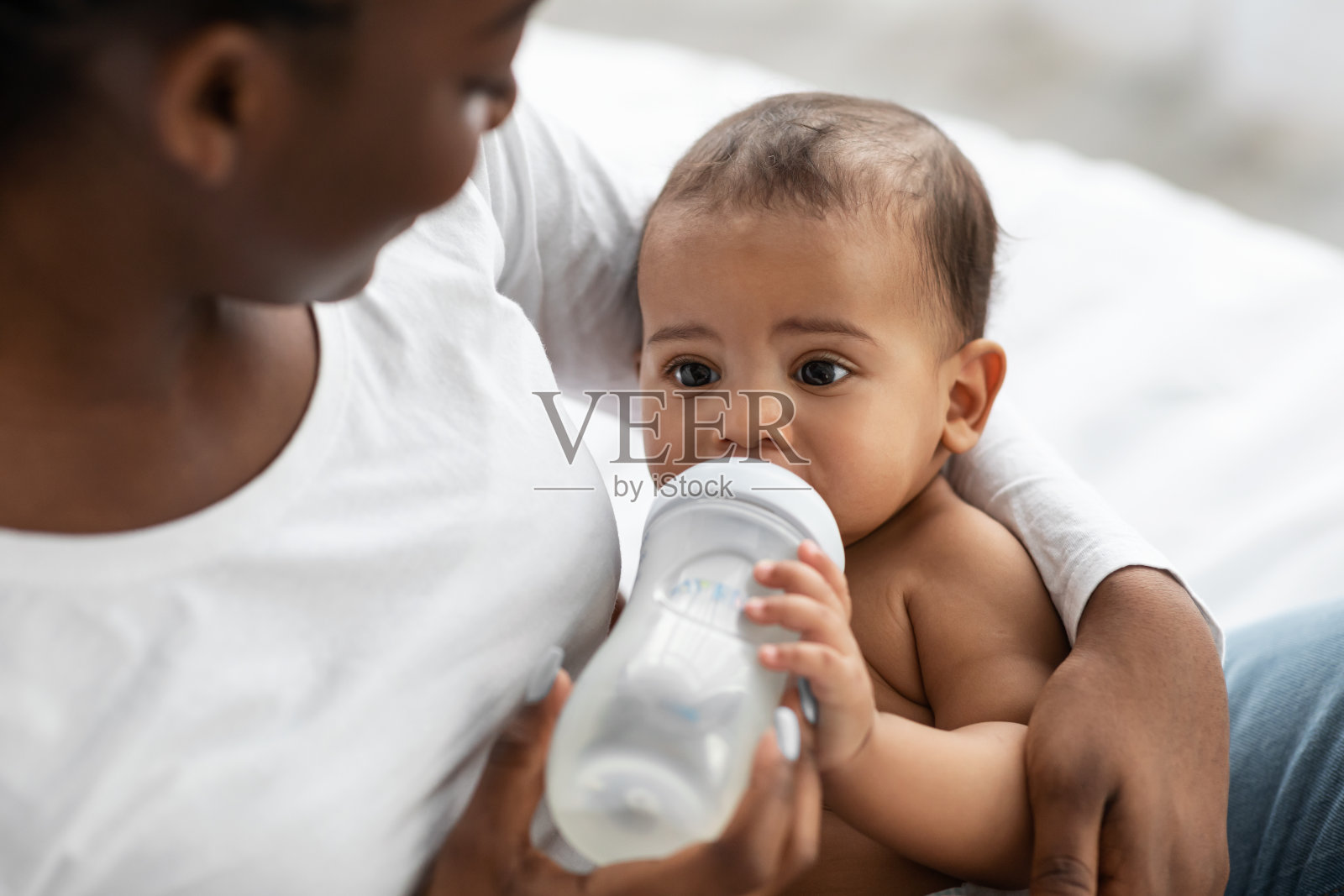 一位非裔美国妇女用奶瓶喂她的孩子照片摄影图片