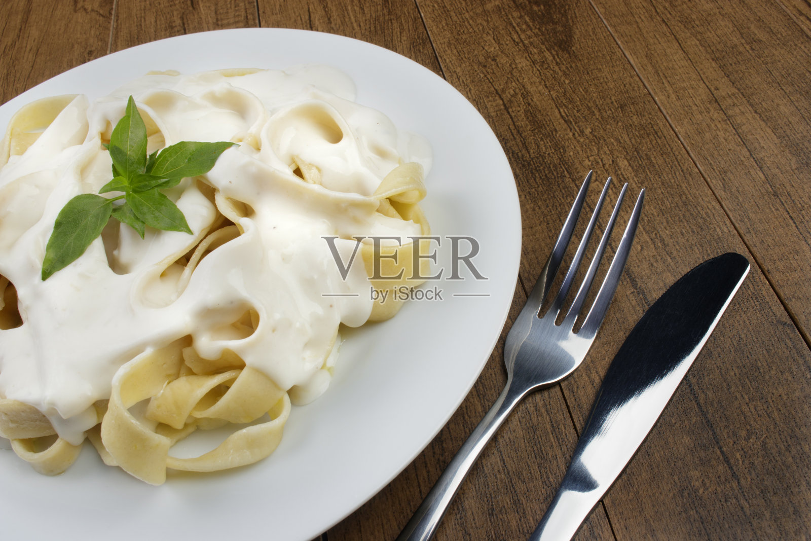 意大利宽面条配白汁和罗勒叶。白酱意大利面。照片摄影图片