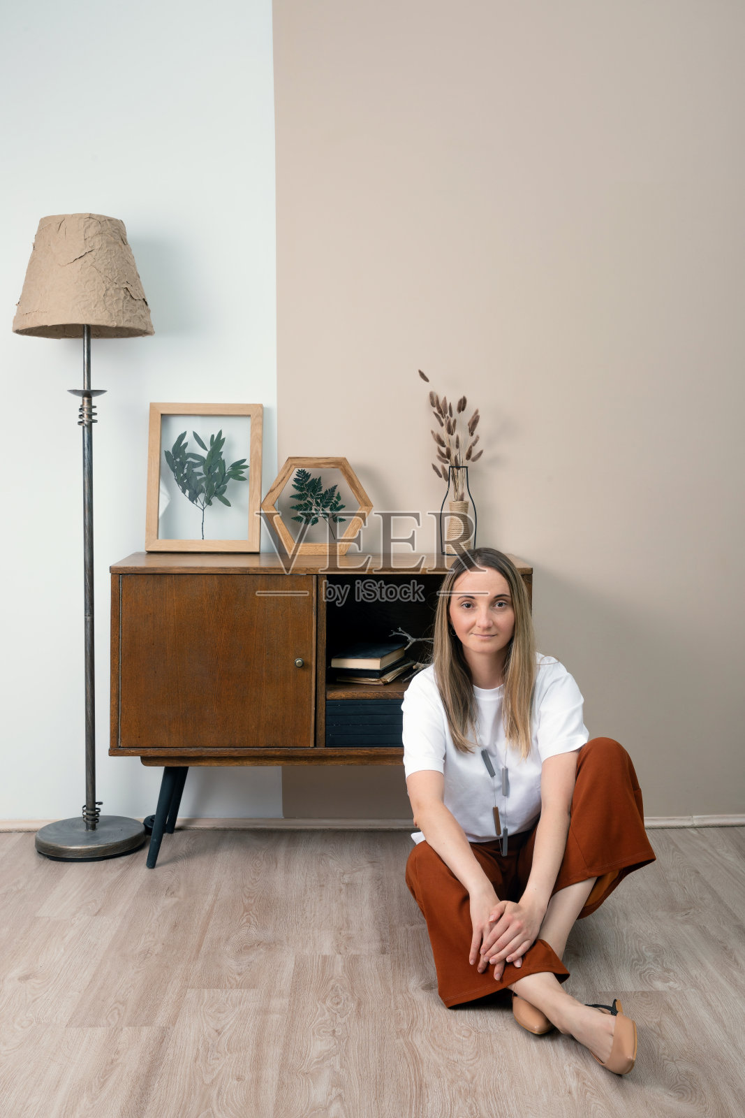 女人在装饰干花的框架。植物叶墙。环保的那种波西米亚风格的装饰。真实的人的私人空间。照片摄影图片