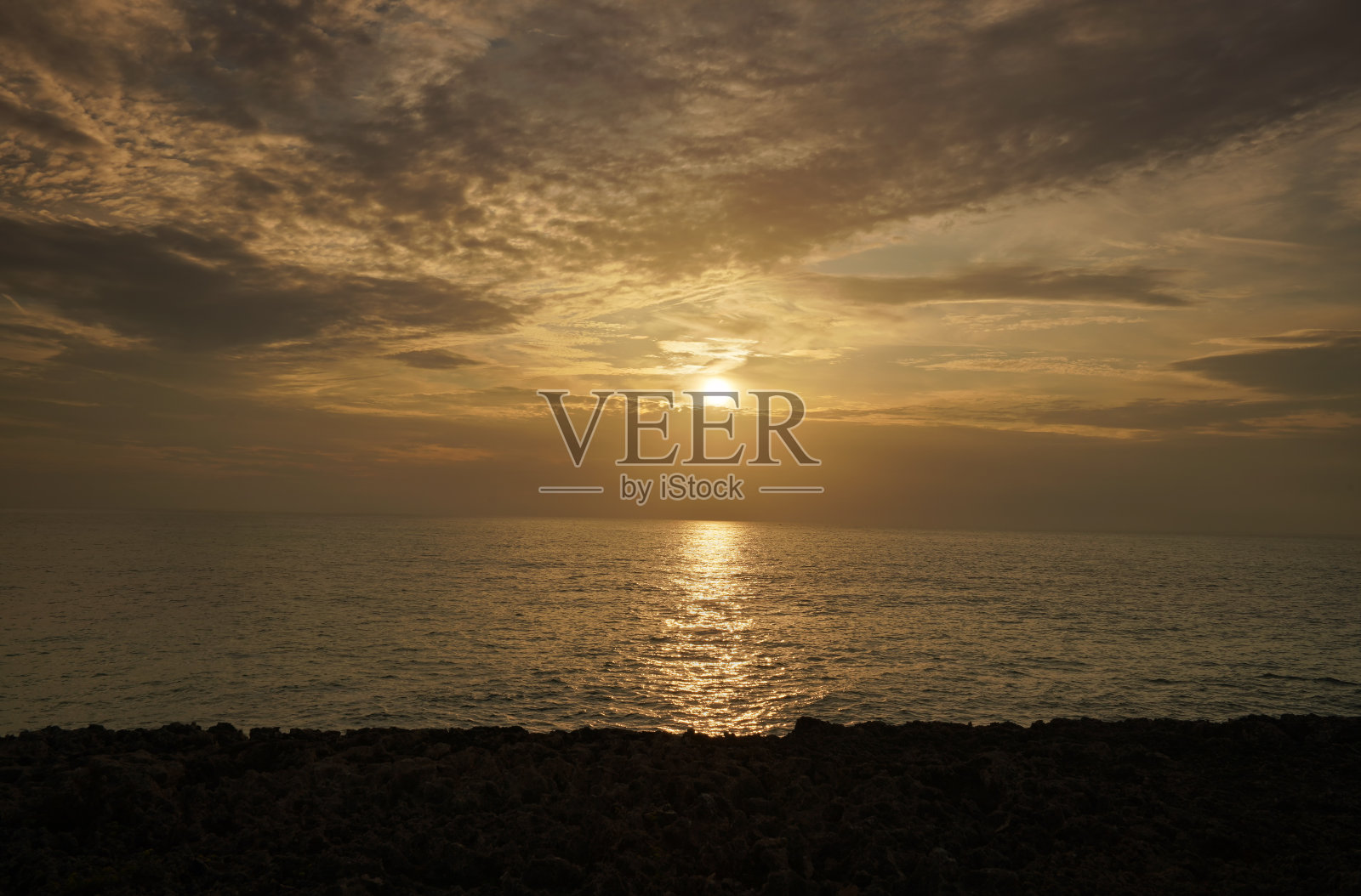 太阳从海面升起，黄光照亮了云朵照片摄影图片