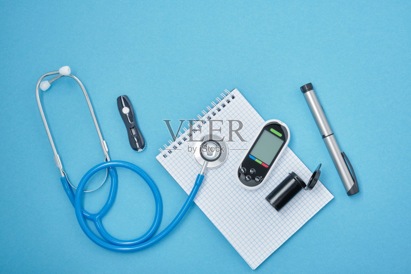 清洁块与弹簧，听诊器，血糖仪，柳叶刀和注射笔与胰岛素在一个蓝色的背景，daibet天概念，糖尿病诊断照片摄影图片