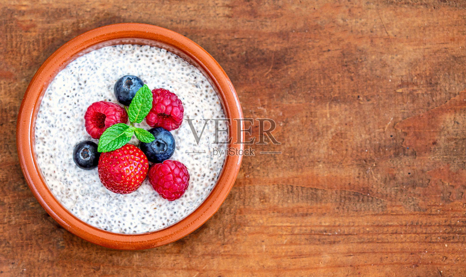 奇亚种子布丁由水果和新鲜的浆果在木材的背景。芡欧鼠尾草种子酸奶。照片摄影图片