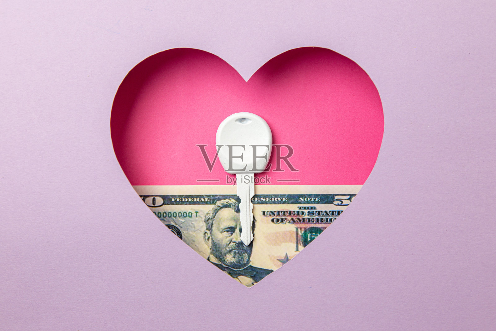 这把钥匙和50美元的钞票在紫色的背景上有一颗粉红色的心。照片摄影图片