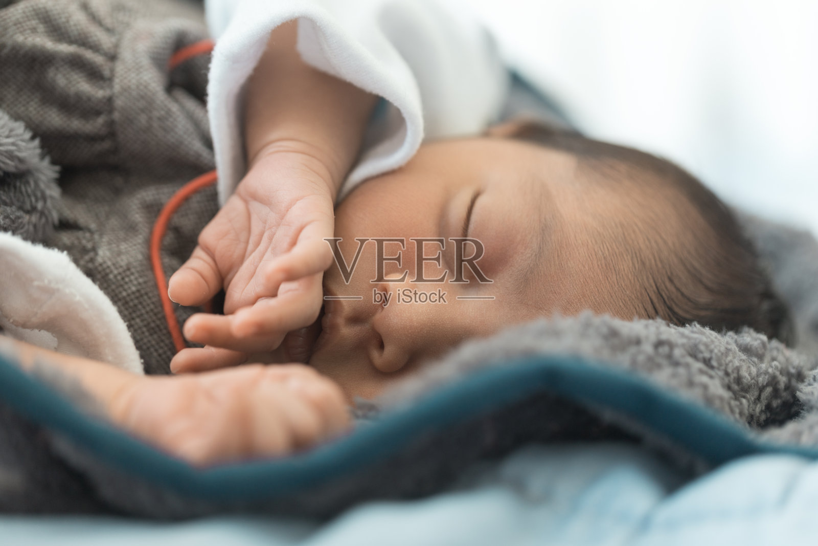 黑发婴儿躺着睡着了，露出双手，穿着白色袖子的胸部，摄影棚拍摄照片摄影图片