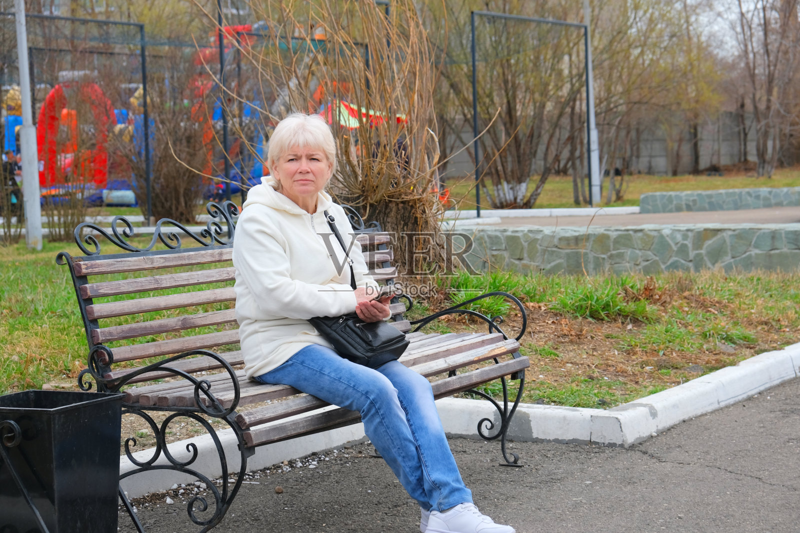 在公园长椅上休息的老妇人。照片摄影图片