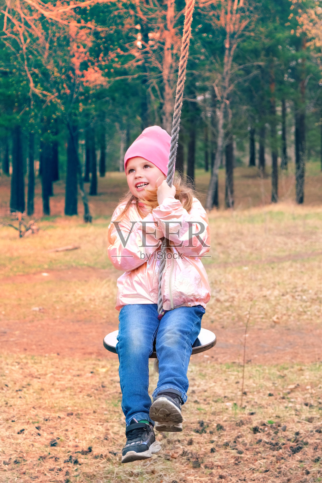 在春天或秋天，孩子们在户外用一根绳子拴在树上的自制秋千上荡秋千。照片摄影图片