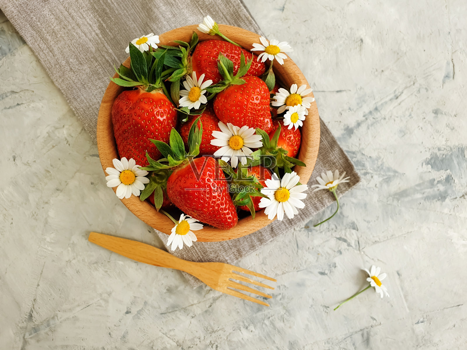 混凝土背景上有新鲜的草莓，洋甘菊花照片摄影图片