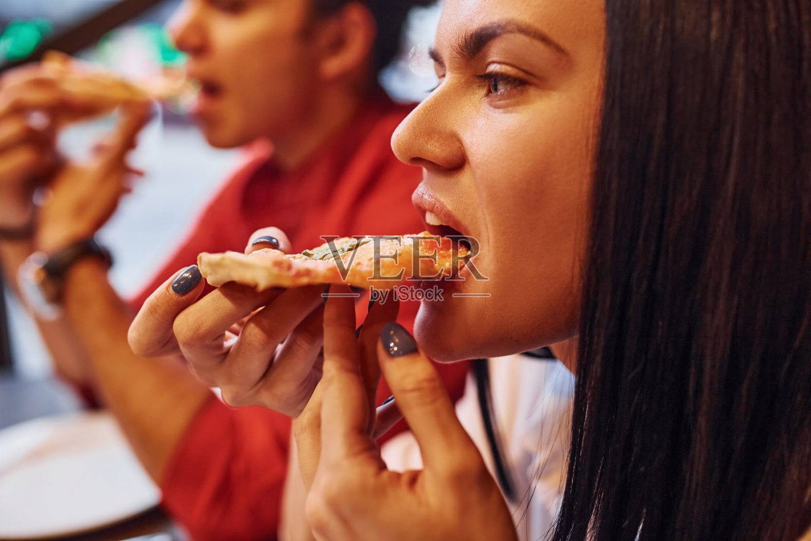 多民族的年轻夫妇坐在室内一起吃披萨照片摄影图片