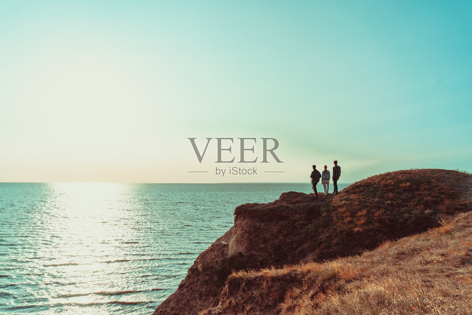 三个人站在靠近大海的山顶上照片摄影图片