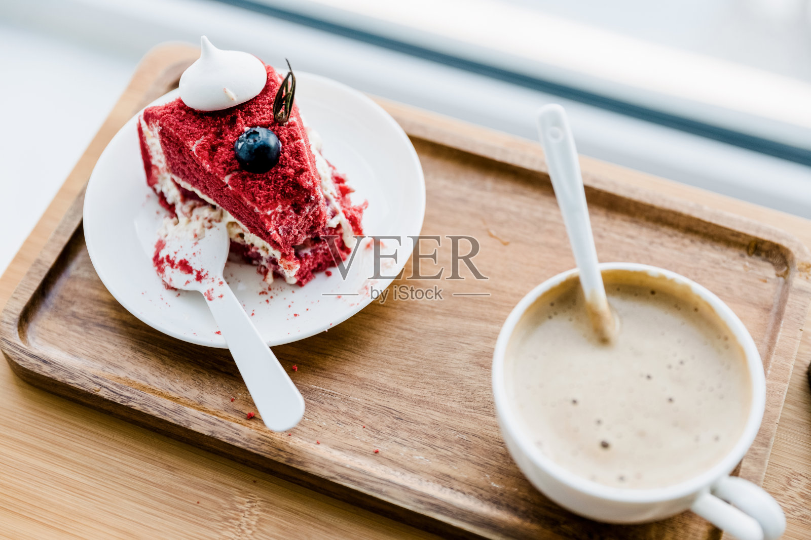 靠近窗户的木桌上放着咖啡和蛋糕照片摄影图片