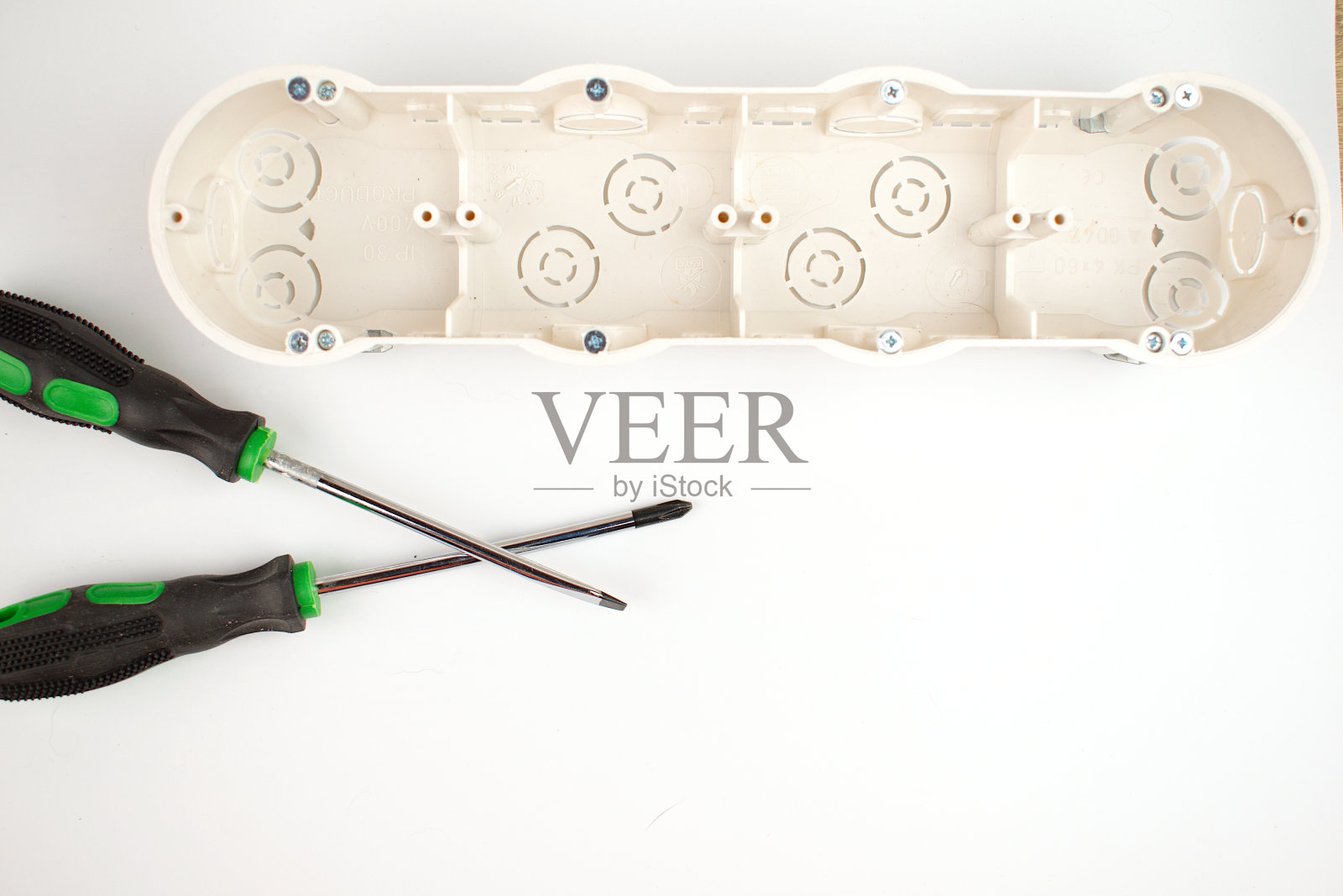 两个螺丝刀和一个插座盒。电工。改造的概念。副本的空间。平的。照片摄影图片