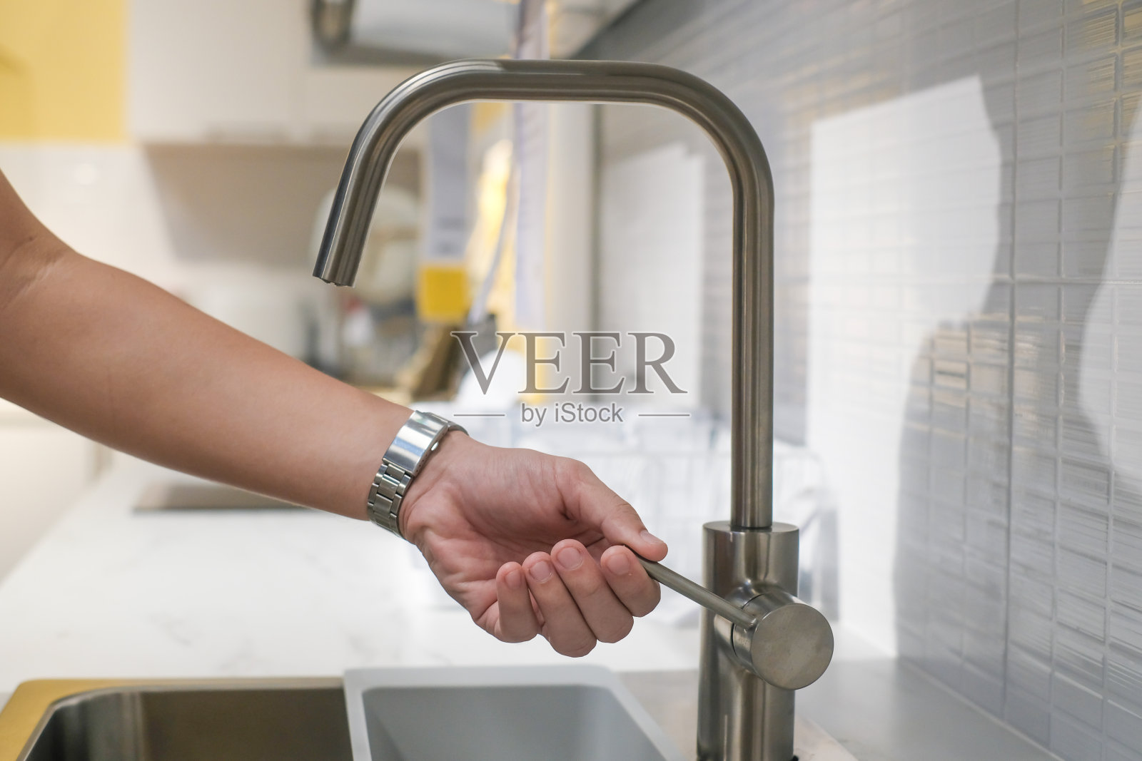 男手在家具店选购不锈钢水龙头。家庭厨房装修。照片摄影图片