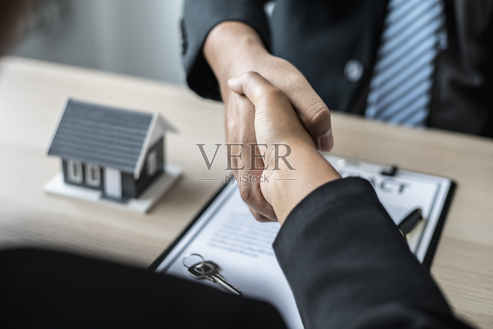 销售人员与客户签订合同后握手，销售人员说明细节并告知客户奖励。买卖房屋的概念。照片摄影图片