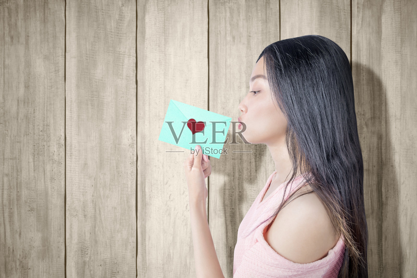 一个亚洲女人拿着一个绿色信封，上面写着爱心照片摄影图片